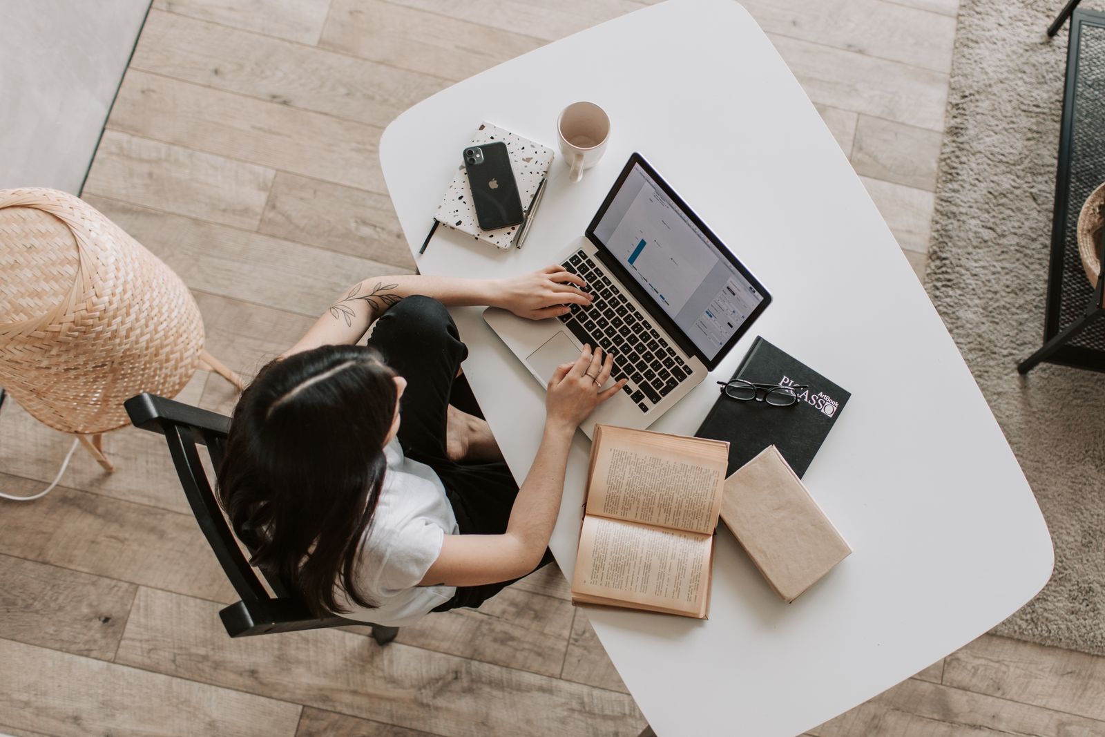 Persona trabajando en un escritorio claro con portátil y libros